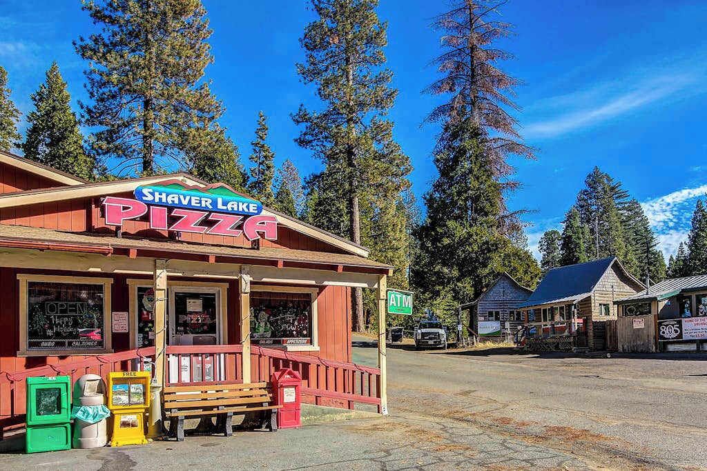 Een pizzeria aan Shaver Lake met een terras, een zichtbare geldautomaat en een heldere lucht.