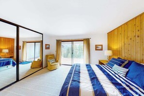 Een hotelkamer met een groot bed, een stoel, een klein tafeltje, een spiegel en uitzicht op het groen.