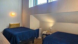 A room with two beds, a small table with a lamp, a fan, and a 'Welcome' pillow. - Huntington Hideaway - Huntington Lake (Lakeshore)