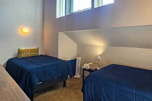 A room with two beds, a small table with a lamp, a fan, and a 'Welcome' pillow. - Huntington Hideaway - Huntington Lake (Lakeshore)