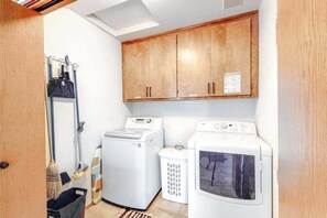 Une buanderie équipée de deux machines à laver, d’un sèche-linge et d’un porte-mop.