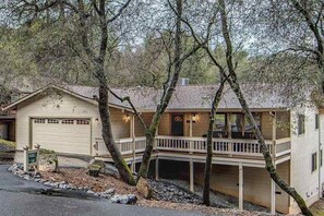 Ein zweistöckiges Haus mit Garage, überdachter Veranda und einer kleinen Terrasse.