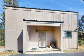 Ein Holzgebäude mit überdachter Veranda und einem kleinen Fenster.