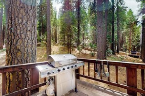 Una terrassa amb una barbacoa, envoltada d'alzines altes.
