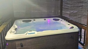 A hot tub with a wooden deck and a covered area. - Cresta Cabin - Pinebrook (Arnold)