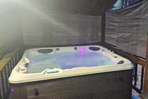 A hot tub with a wooden deck and a covered area. - Cresta Cabin - Pinebrook (Arnold)