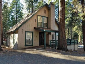 A small wooden cabin with a gabled roof, a front porch, and a chimney. - Casita Villareal - East Village (Shaver Lake)