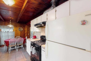 A kitchen with a stove, refrigerator, and dining table with chairs. - Casita Villareal - East Village (Shaver Lake)