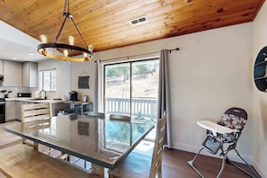 Une cuisine moderne avec une table à plateau en verre, un plafond en bois et une vue sur l’extérieur.