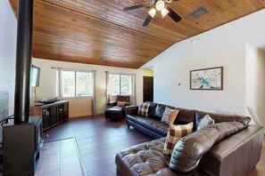 A living room with a fireplace, leather sofa, and a ceiling fan. - Pine Mountain Retreat (Groveland)
