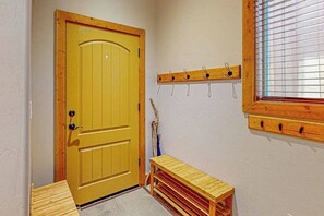 Une porte en bois avec une poignée, un porte-manteau avec des crochets et une fenêtre avec des stores.