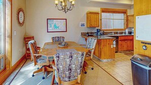 Una sala da pranzo con un tavolo e sedie in legno, un lampadario e un angolo cottura con pensili in legno e una finestra.