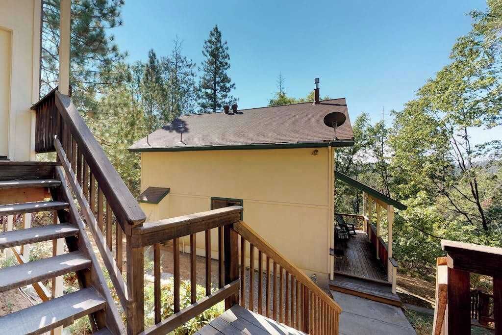 Una escalera de madera que lleva a una terraza con mobiliario exterior.