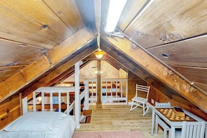 Ein gemütliches Schlafzimmer im Dachgeschoss mit Holzbalkendecke, einem Bett, einem kleinen Tisch und einem Stuhl.