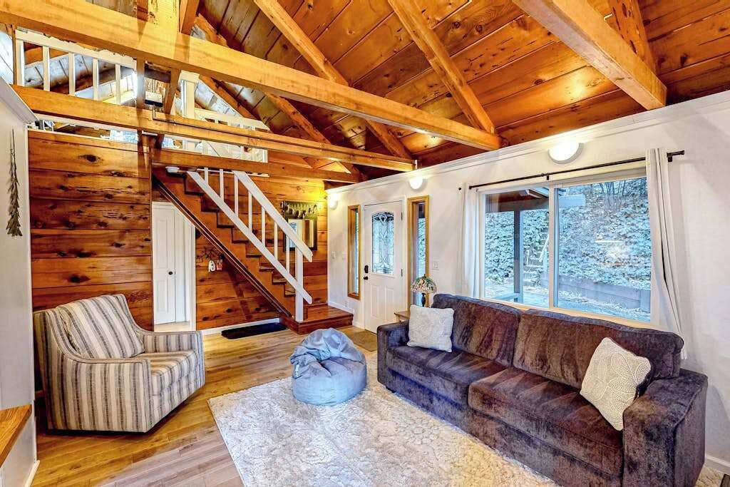 Un interior de madera con una escalera, un sofá y una ventana.