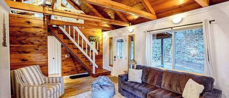 Un interior de madera con una escalera, un sofá y una ventana.