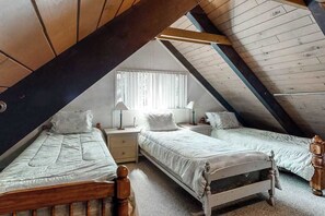 A bedroom with two single beds, wooden headboards, a nightstand, a lamp, and a window with curtains. - Snowpeak Chalet - Big Trees Village (Camp Connell)