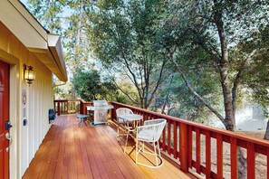 Eine Holzterrasse mit Gartenmöbeln, einem Grill und einem roten Geländer.