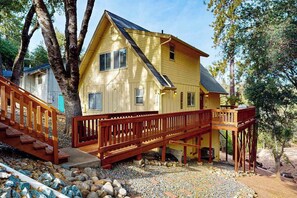Ein zweistöckiges Haus mit einer Holzterrasse und einer Treppe, die zu einem Balkon führt.