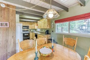 A dining area with a round wooden table, chairs, a decorative bowl, and candle holders.