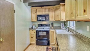 Una cocina compacta con muebles de madera, microondas, horno y pileta.