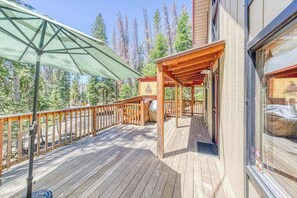 A wooden deck with a pergola and a covered seating area, surrounded by trees.