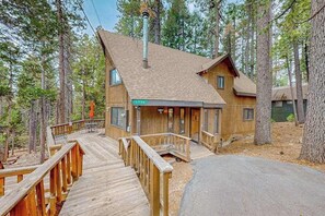 A wooden cabin with a deck, surrounded by trees. - Forest Retreat - Blue Lake Springs (Arnold)