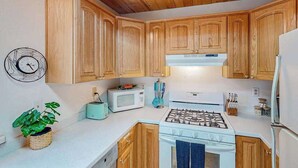 Eine Küche mit Holzausstattung, einem Gasherd, einer Mikrowelle und einem Toaster.