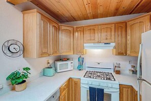 A kitchen with wooden cabinets, a gas stove, a microwave, and a toaster. - Forest Retreat - Blue Lake Springs (Arnold)