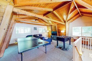A cozy loft-style room with a ping pong table, a foosball table, and a comfortable seating area. - Cozy Cabin - Pine Mountain Lake (Groveland)