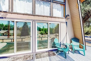 A covered deck with a glass enclosure, two chairs, and a table. - Cozy Cabin - Pine Mountain Lake (Groveland)