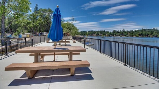 A riverside walkway with picnic tables and a blue umbrella. - Cozy Cabin - Pine Mountain Lake (Groveland)