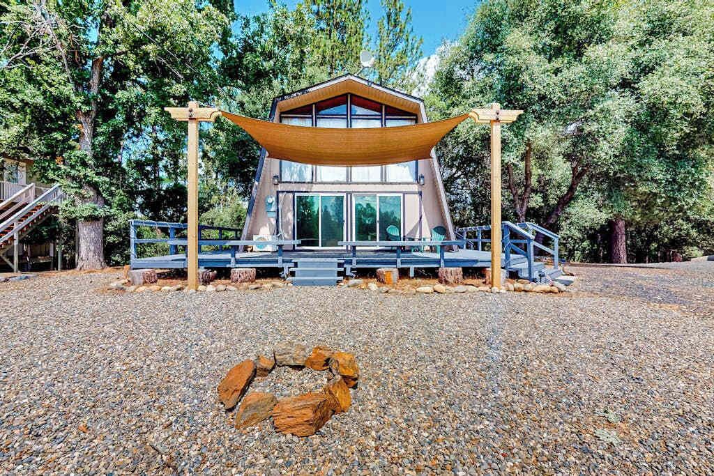 A modern building with a wooden deck, surrounded by trees and gravel.