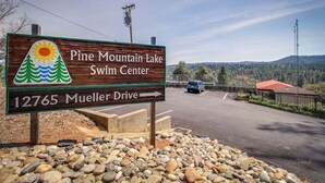 A wooden sign for Pine Mountain Lake Swim Center with an arrow pointing to Mueller Drive. - Cozy Cabin - Pine Mountain Lake (Groveland)