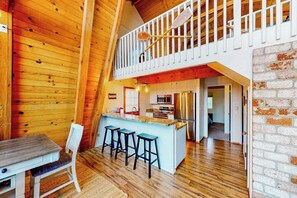 A wooden interior with a dining area, kitchen, and a loft space. - Cozy Cabin - Pine Mountain Lake (Groveland)