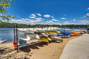 A row of canoes and kayaks lined up on a sandy beach by a calm lake with a clear sky. - The Lake Haus - Pine Mountain Lake (Groveland)