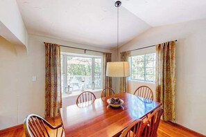 A dining area with a wooden table, chairs, a bowl of fruit, and a hanging lamp. - The Lake Haus - Pine Mountain Lake (Groveland)