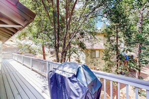 A wooden deck with a covered grill, surrounded by trees and a house in the background. - The Lake Haus - Pine Mountain Lake (Groveland)
