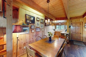 Ein Holzinterieur mit einem Esstisch, Stühlen und einer Hängeleuchte.