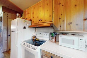 Eine Küche mit Holzausstattung, einem Kühlschrank, einem Herd und einer Mikrowelle.