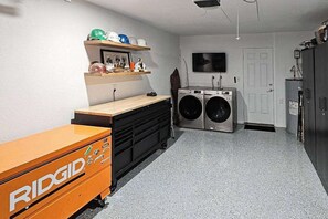 A laundry room with a washing machine, dryer, and a cabinet with a logo. - Jordan Oak - Pine Mountain Lake (Groveland)