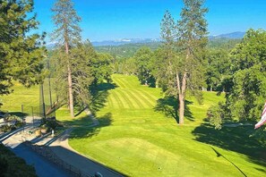 Ein Golfplatz mit freiem Blick auf die Spielbahn, umgeben von Bäumen und einem fernen Gebirge.