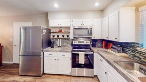 Una cocina moderna con electrodomésticos de acero inoxidable, armarios blancos y un salpicadero de azulejos.