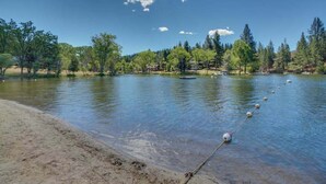 Un lago tranquilo con aguas cristalinas, rodeado de árboles y una orilla arenosa.