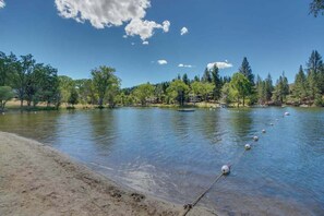 Ein ruhiger See mit klarem Wasser, umgeben von Bäumen und einem sandigen Ufer.