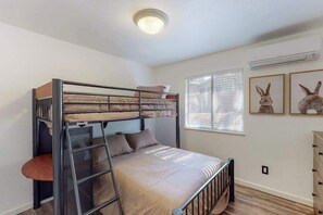 A bunk bed room with a ladder, a window with blinds, and two framed pictures on the wall. - Holiday Chalet - Pine Mountain Lake (Groveland)