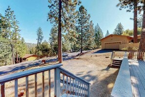 A residential property with a wooden deck, a garage, and a driveway surrounded by pine trees. - Holiday Chalet - Pine Mountain Lake (Groveland)