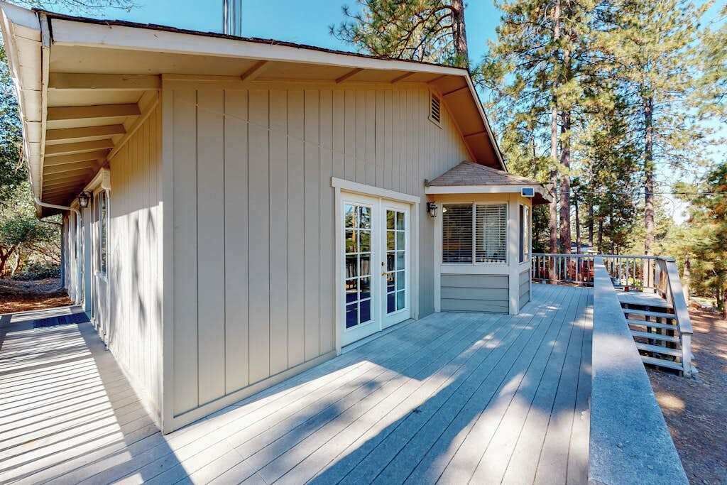A wooden deck leading to a building with a covered porch and a small attached structure.