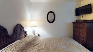 A bedroom with a bed, a dresser, a TV, and a wall-mounted mirror. - Foxtail Delight - West Village (Shaver Lake)