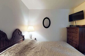 A bedroom with a bed, a dresser, a TV, and a wall-mounted mirror. - Foxtail Delight - West Village (Shaver Lake)